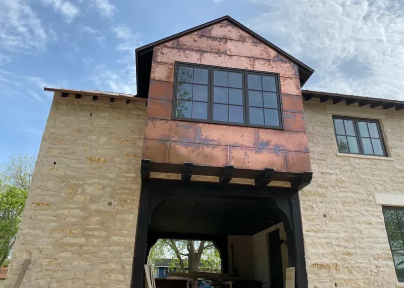 Copper metal panel facade on a stone building for Roof Repair in Bentonville